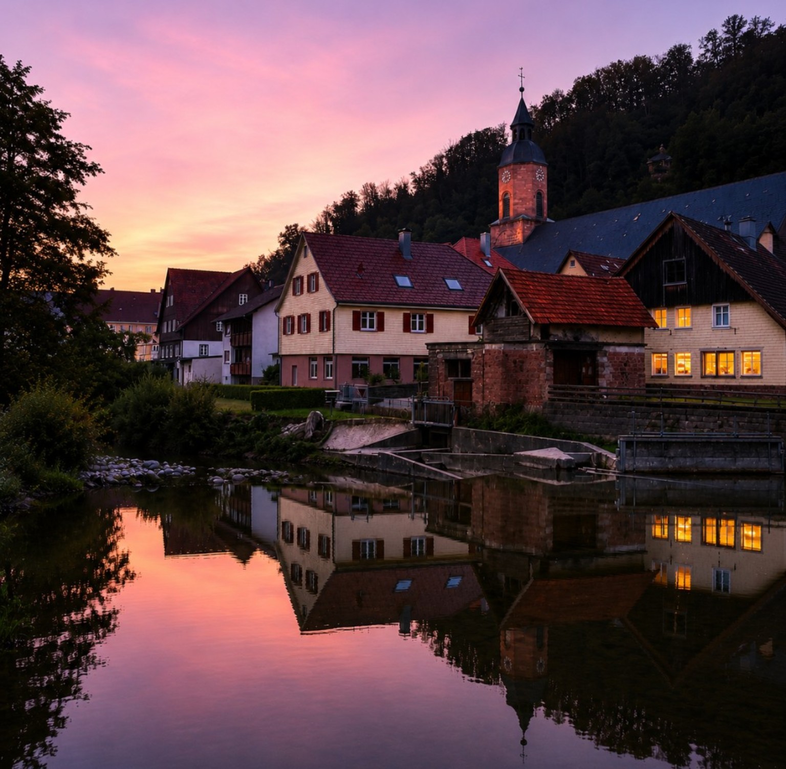 Village and church tower reflected in water at twilight