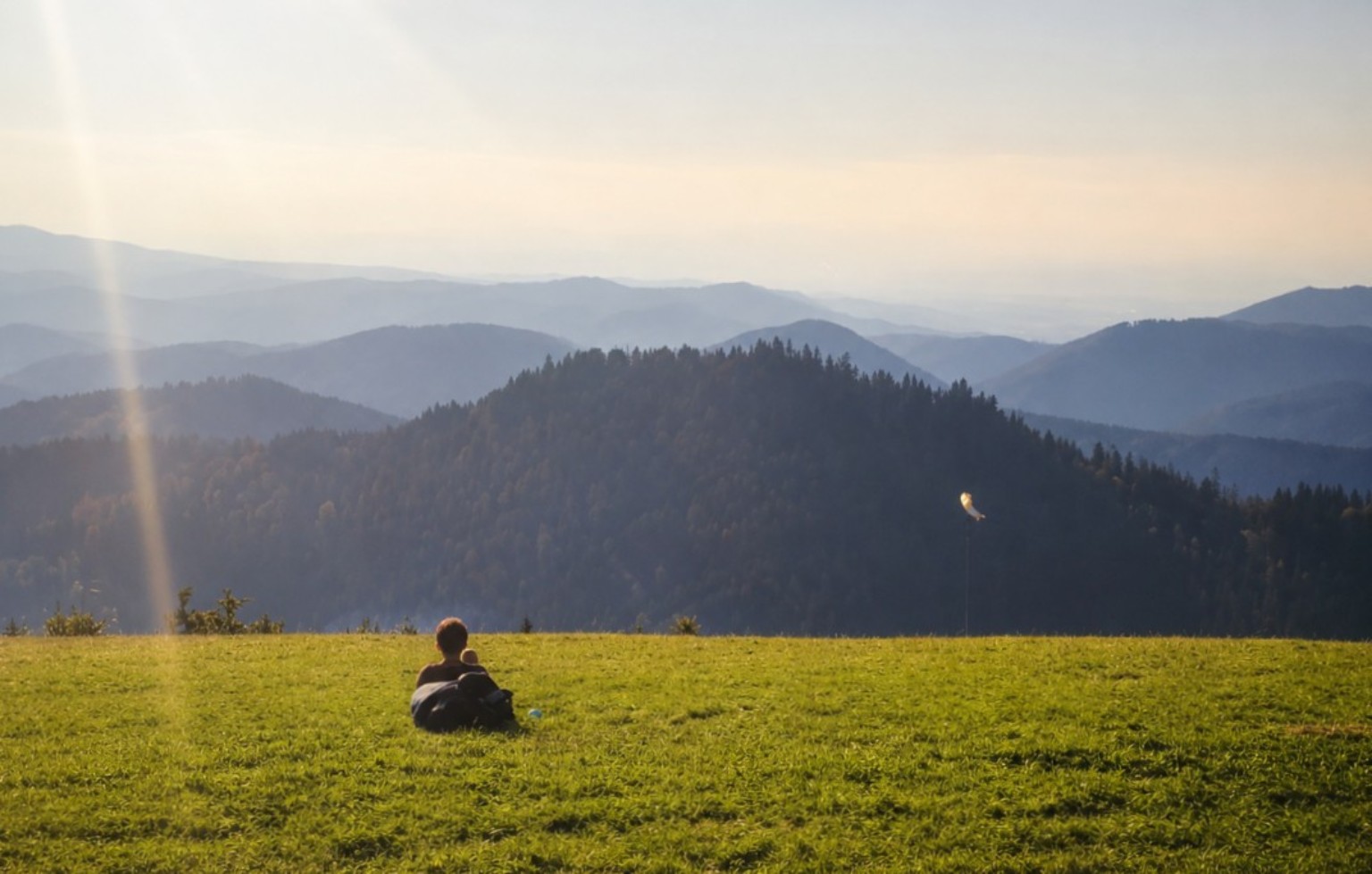 Figures resting before layered mountain ridges